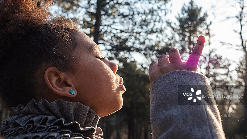 快乐童年：非裔美国女孩在公园里吹泡泡图片素材