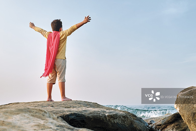 在海边岩石上眺望远方的超级英雄儿童图片素材