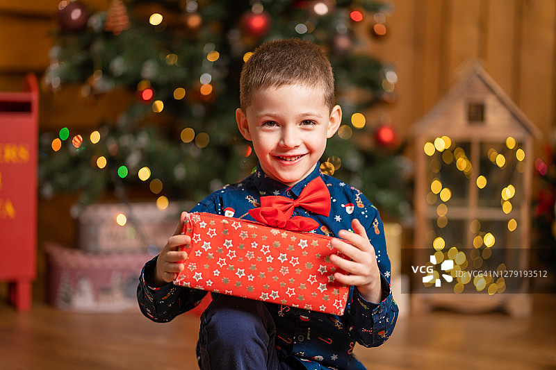 圣诞节：小男孩抱着来自圣诞老人的红色大礼盒图片素材