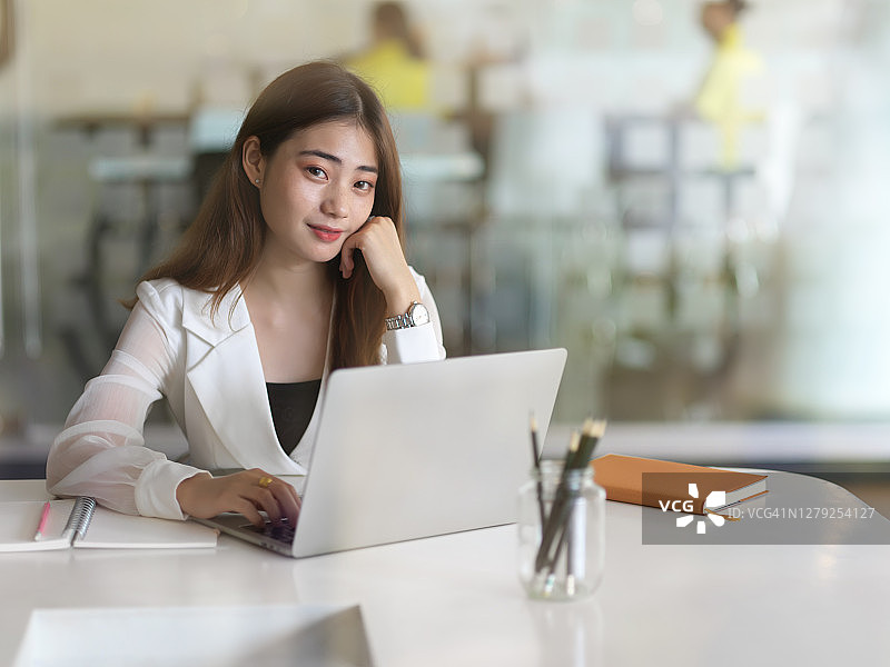 在办公室的办公桌上使用笔记本电脑的女人图片素材