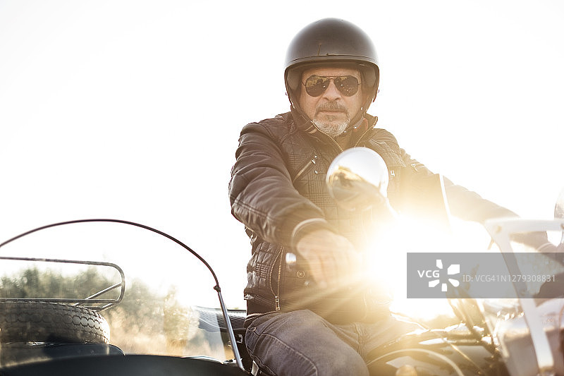 坐在挎斗摩托车里的中年男人，看着镜头图片素材