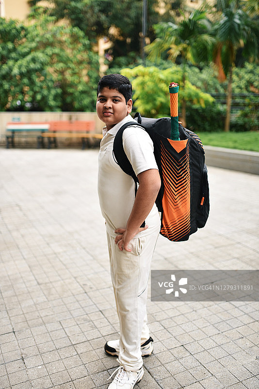 男孩肩扛板球装备包，身穿板球服图片素材