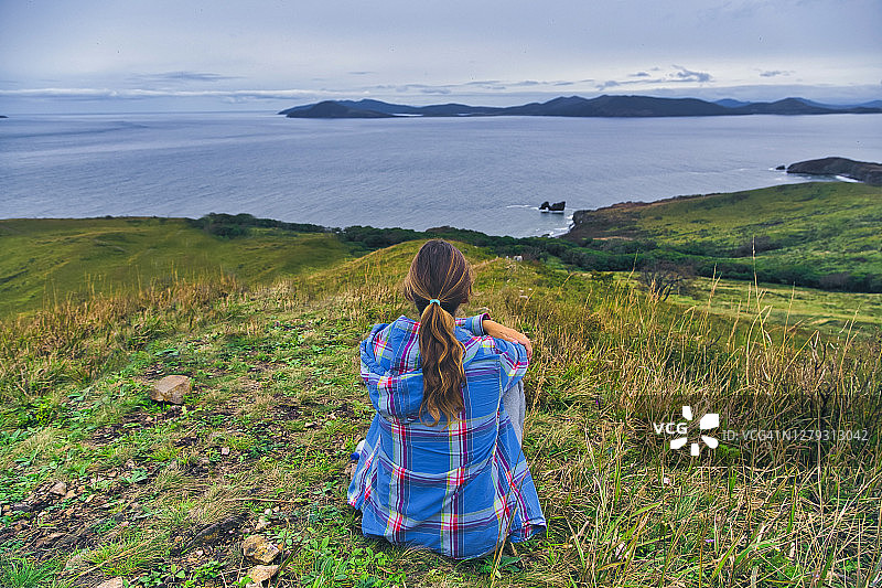 女人坐在俄罗斯克拉贝半岛的山上看着日本海图片素材