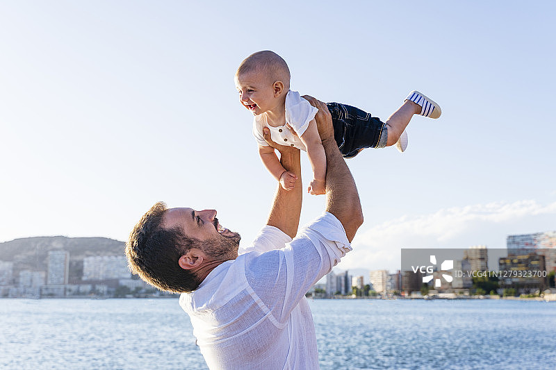 日落时分，父亲抱着儿子站在海边图片素材