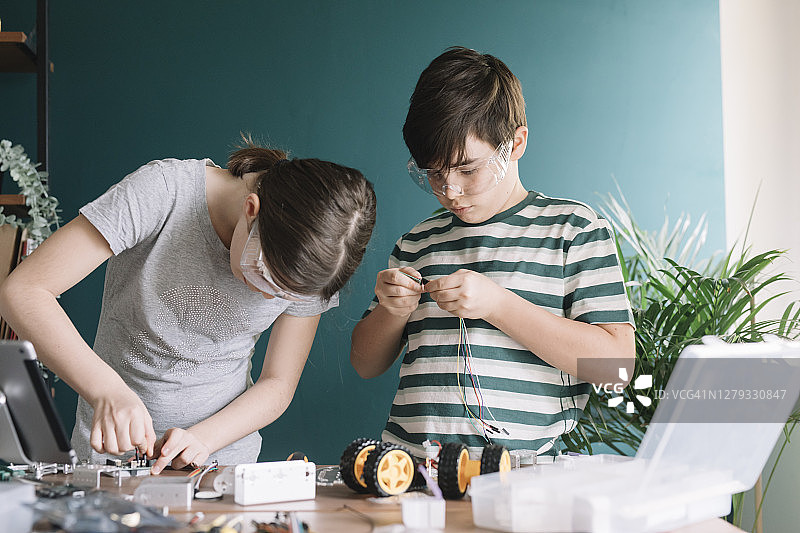 兄妹在家里的桌子上制作机器人玩具图片素材