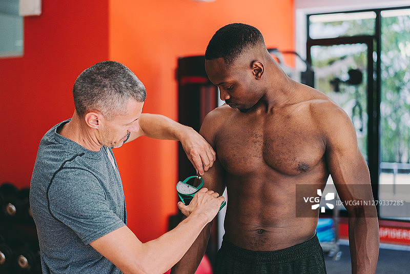 教练用卡尺测量客户的身体脂肪图片素材