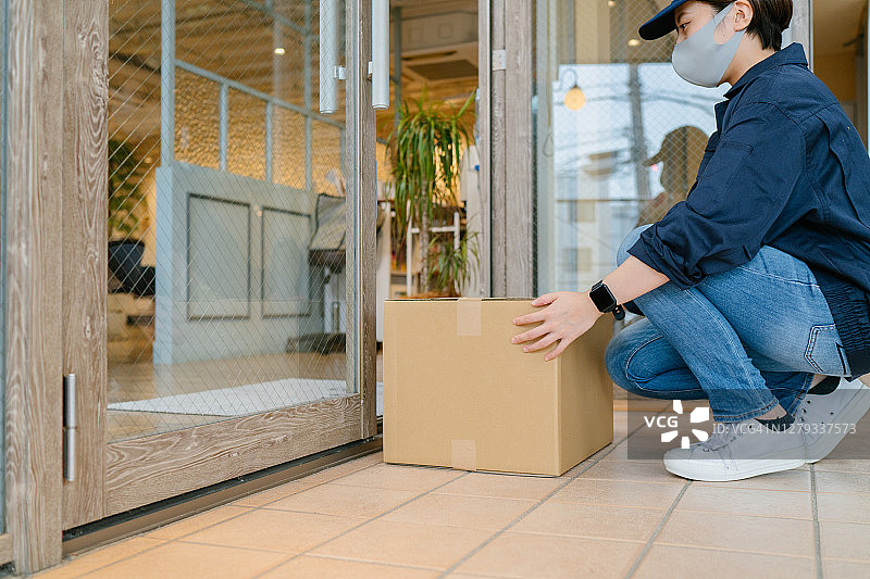 配送员将包裹放置在小商店的门口图片素材