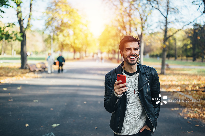在秋日公园里享受音乐的男人图片素材