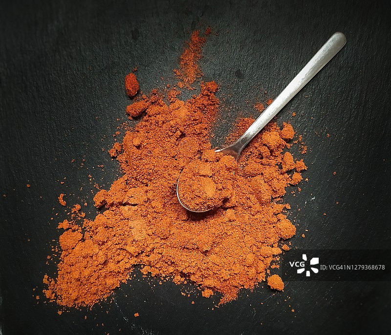 黑色石板背景下盛有香料的勺子图片素材