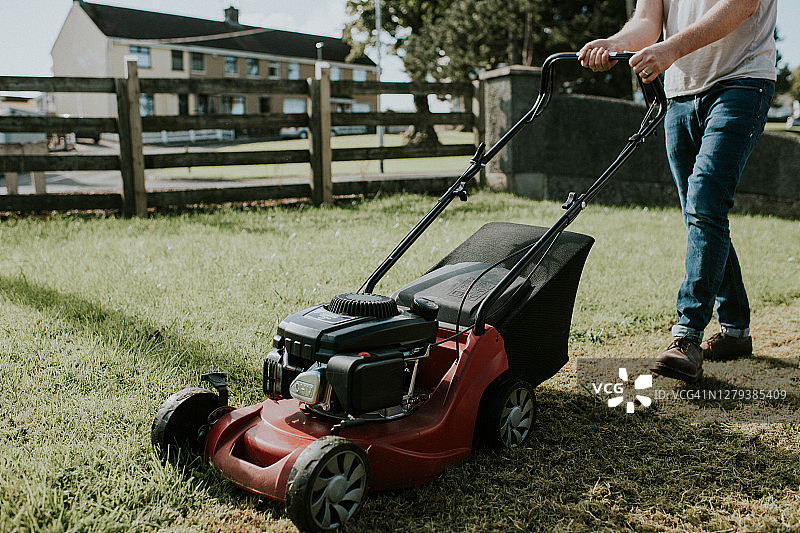 男人在花园里推动割草机图片素材