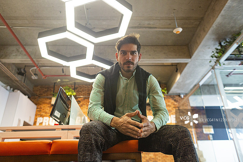 拉美裔男人坐在办公室里，看向镜头图片素材