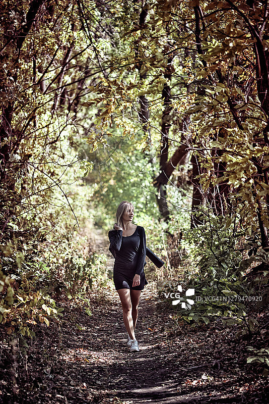 在秋季森林中行走的年轻女人图片素材