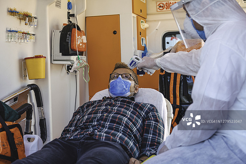 疫情期间，身穿防护服的护理人员在救护车内测量患者体温图片素材