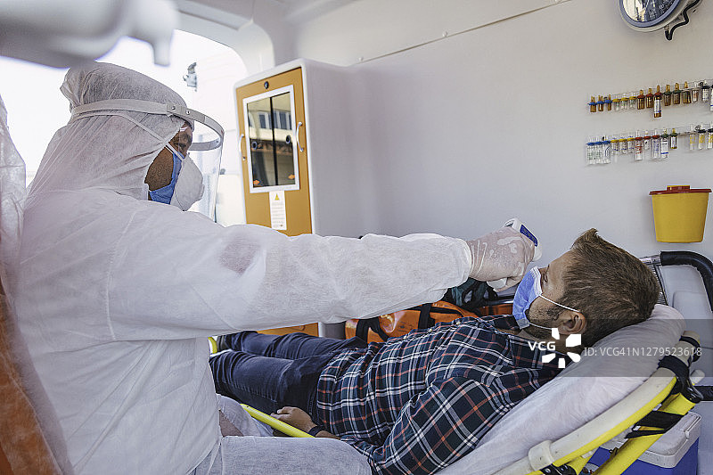 疫情期间，身穿防护服的护理人员在救护车内测量患者体温图片素材