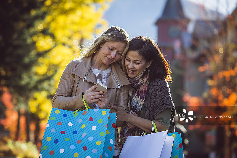 两位女人提着购物袋走过惠斯勒村图片素材