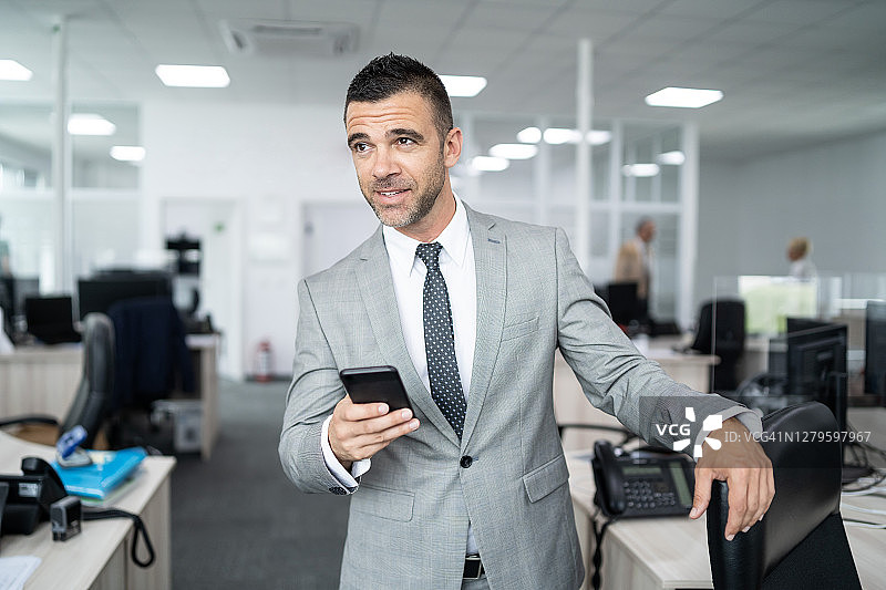 Мanager在他的办公室，使用他的智能手机图片素材
