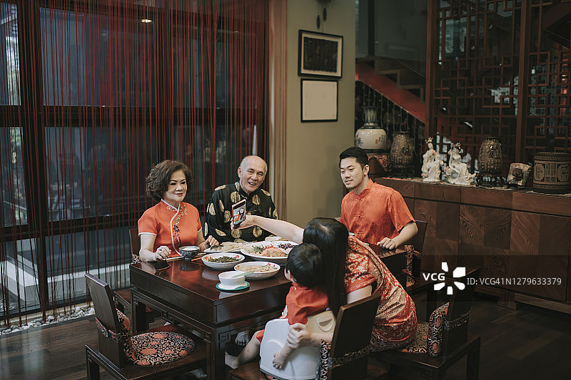 亚洲华人家庭中国新年团圆饭，享用传统菜肴捞生鱼生图片素材