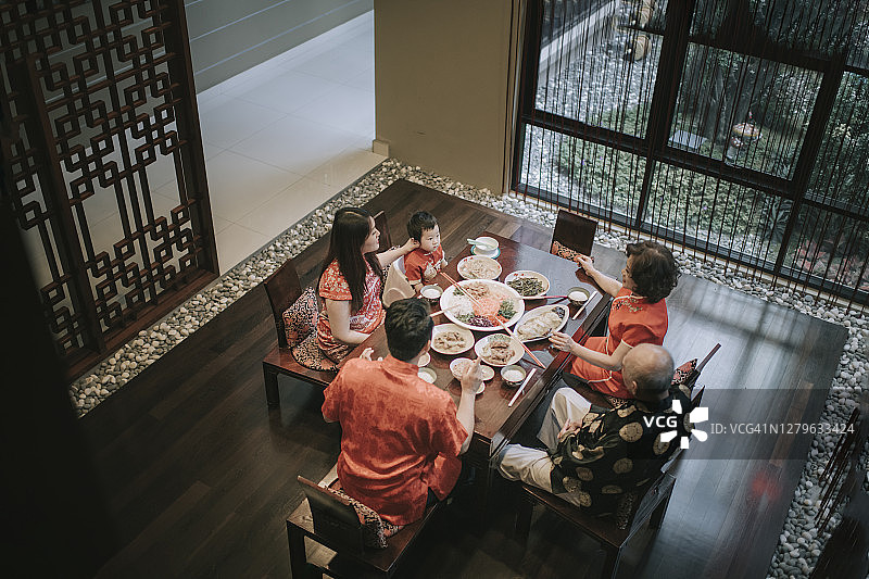 亚洲华人家庭中国新年团圆饭，享用传统菜肴捞生鱼生图片素材
