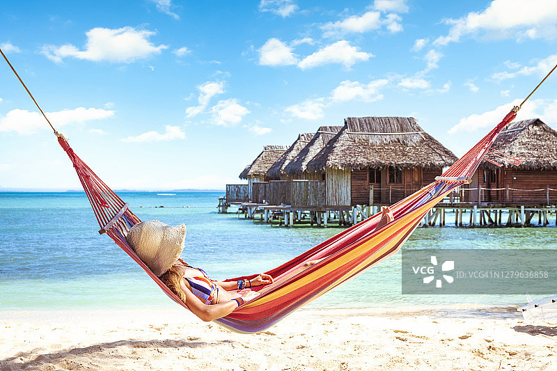 游客在海边和水上木屋附近的吊床上放松图片素材
