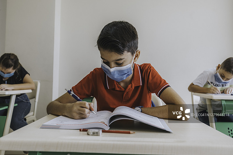 疫情期间戴口罩在课堂上学习的男学生图片素材