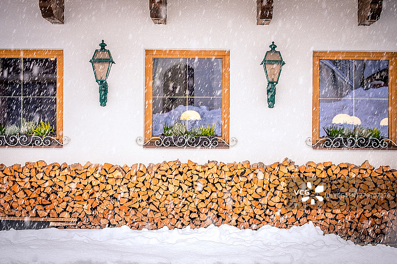 奥地利斯图拜山谷诺伊斯蒂夫特市的冬季景观，典型奥地利房屋的窗户前堆放着柴火图片素材
