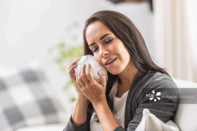 脸上带着微笑，用冰袋敷脸的女人浮雕图片素材