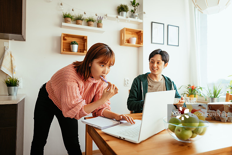 在厨房一起吃饭时使用电子银行的日本女人。网络研讨会前刷牙的女人。图片素材