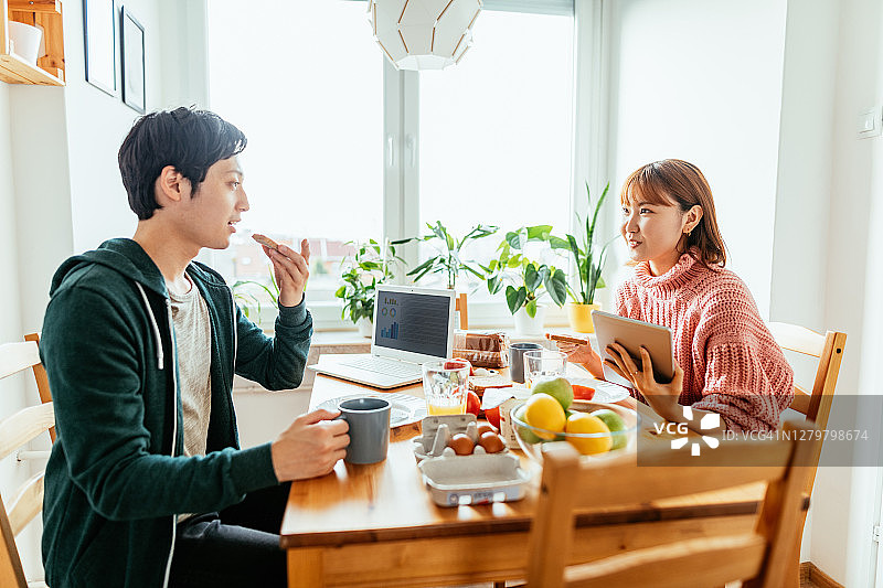 日本夫妇在家一起用餐，使用科技产品进行远程办公图片素材