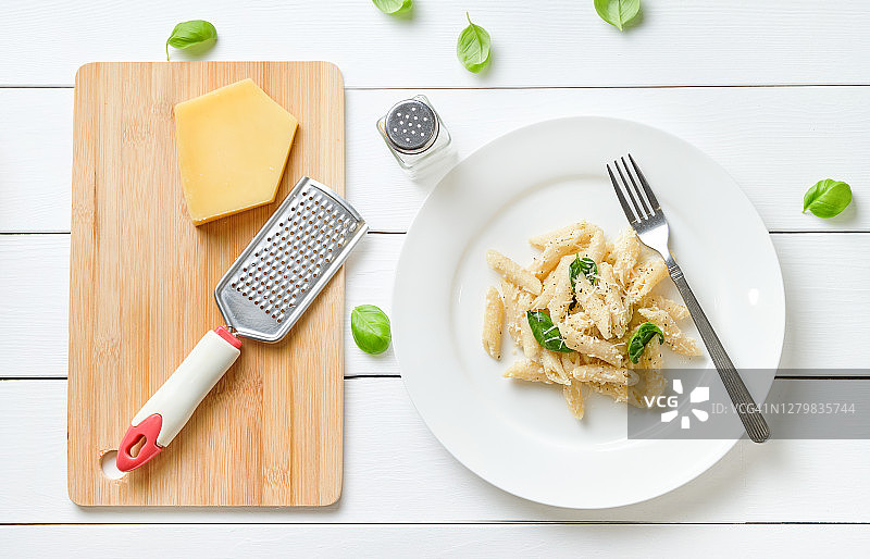 在家烹饪奶油罗勒意大利面：将帕尔马干酪磨碎并加入意面中，纯素食品，分步教学第11步。图片素材