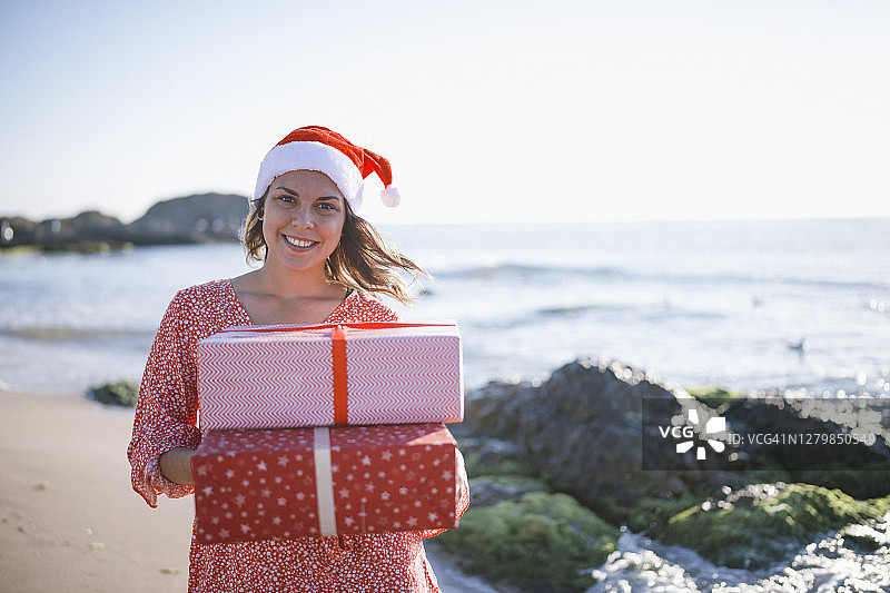 微笑的女子在海滩上拿着圣诞礼物图片素材