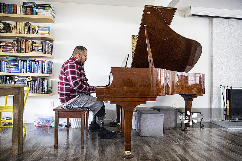 弹钢琴的西班牙裔退伍截肢军人图片素材