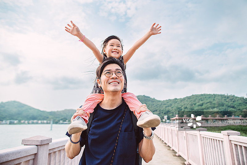 可爱的小女孩快乐地坐在爸爸的肩膀上图片素材