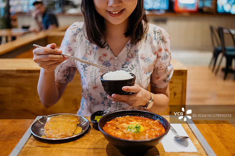 吃韩式嫩豆腐汤和一碗白米饭的微笑亚洲女性图片素材