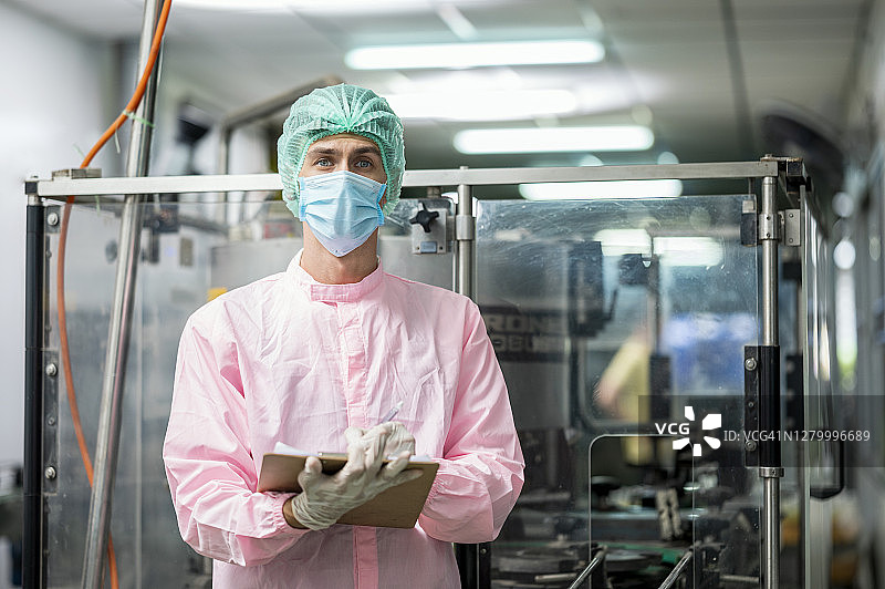 食品饮料行业：穿防护服的工人在罗勒籽饮料自动化生产线上工作图片素材