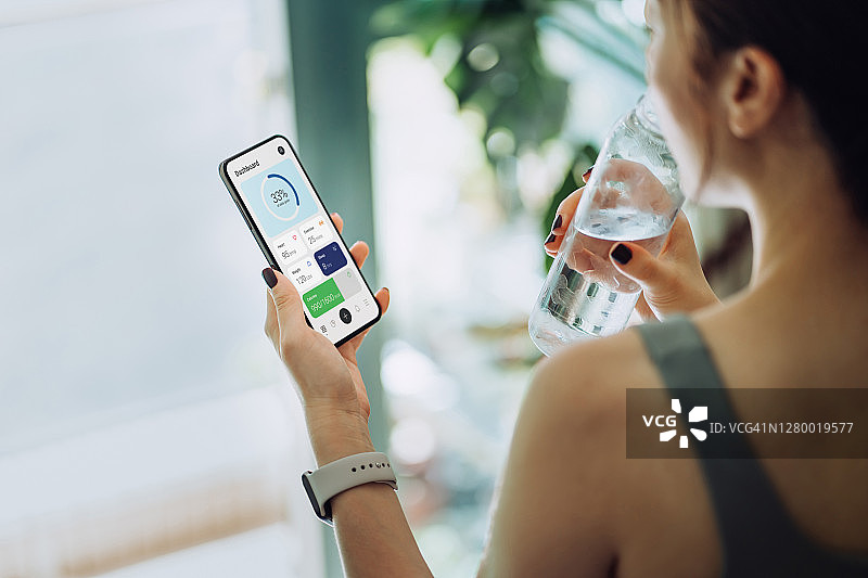 亚洲年轻运动女性在运动后使用手机健身App图片素材