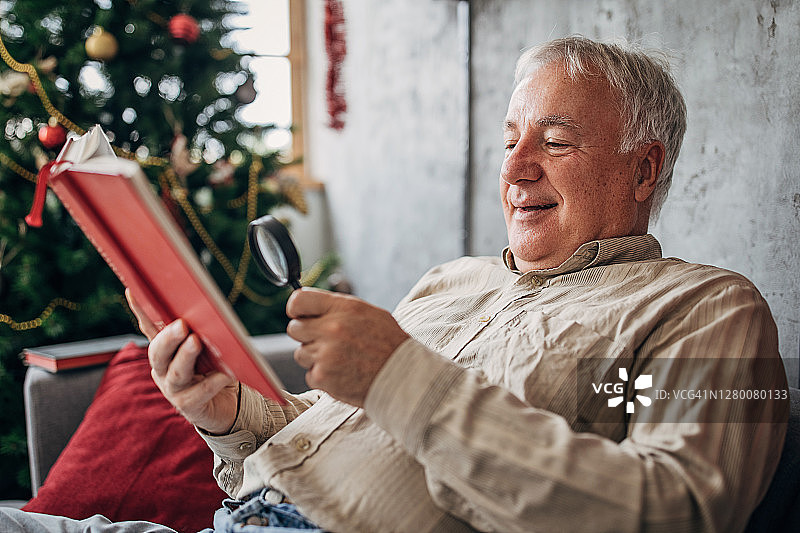 年长的男人在放大镜的帮助下读书图片素材