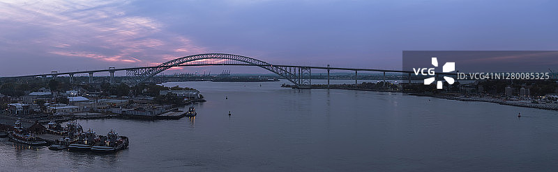 日落时分，拖船停泊在新泽西州和纽约州之间的巴约讷大桥前，远处可以看到商业码头和港口。高分辨率拼接全景图。图片素材