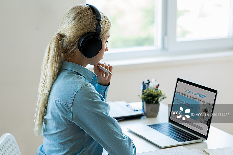 戴耳机学生在家用笔记本电脑观看视频图片素材