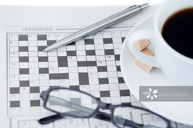 一杯咖啡、一支笔、一副眼镜和一个填字游戏图片素材