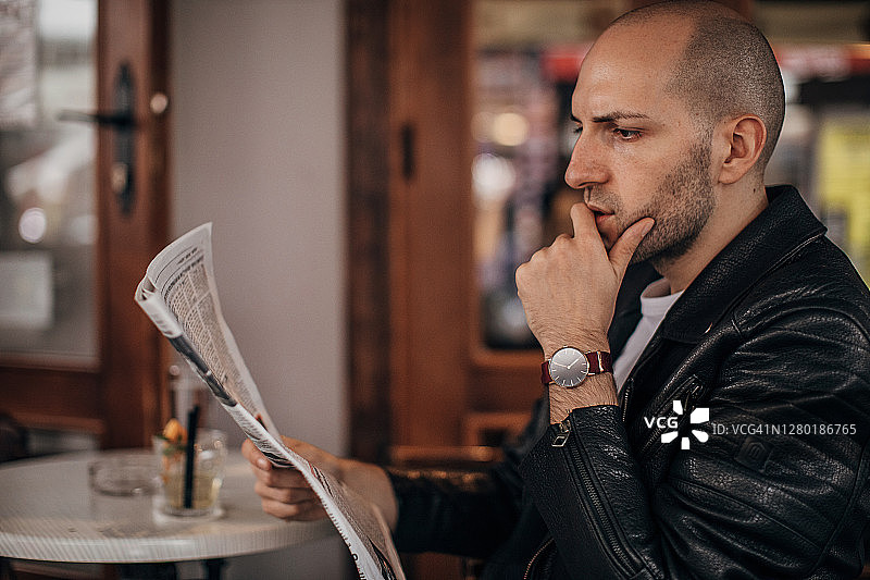 男人坐在路边咖啡馆看报纸图片素材