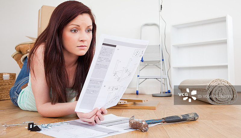 红发女子在地板上阅读DIY手册图片素材