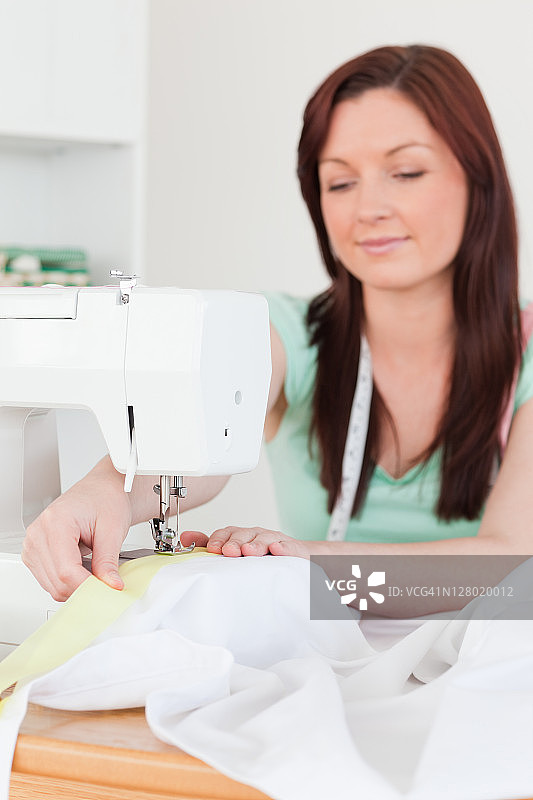 使用缝纫机的漂亮红发女人图片素材