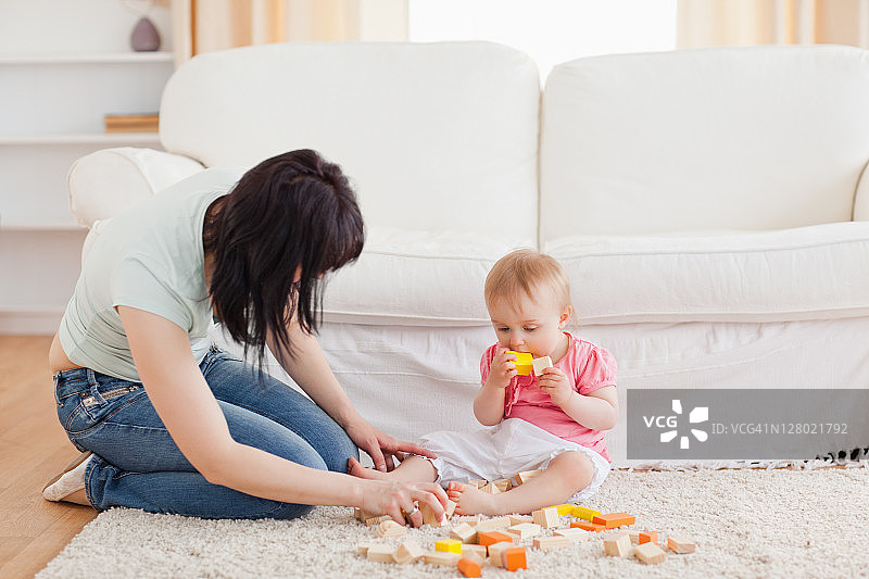 坐在地毯上和宝宝玩耍的有魅力的女人图片素材