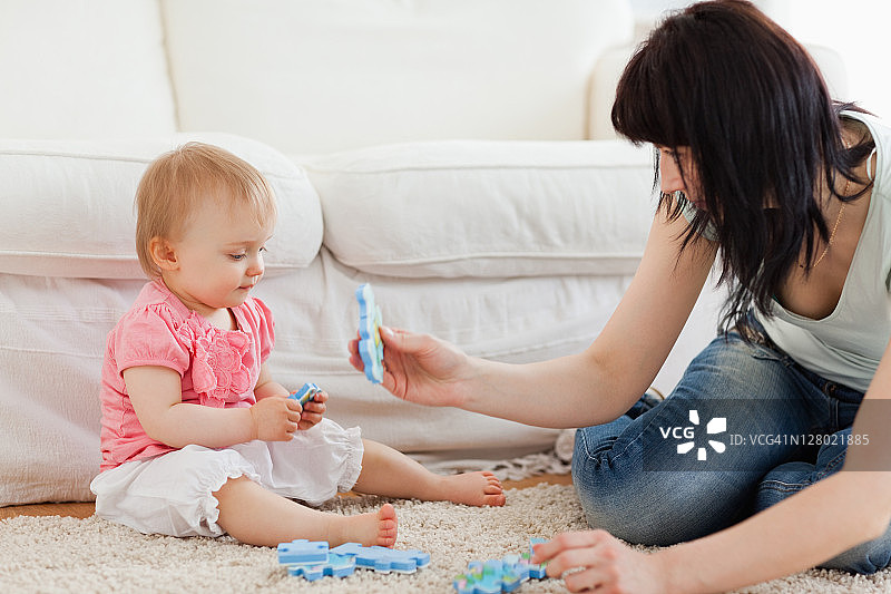 美丽女人和宝宝在地毯上玩拼图图片素材