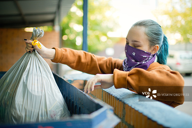 戴着另类面巾的年轻女孩准备扔垃圾图片素材