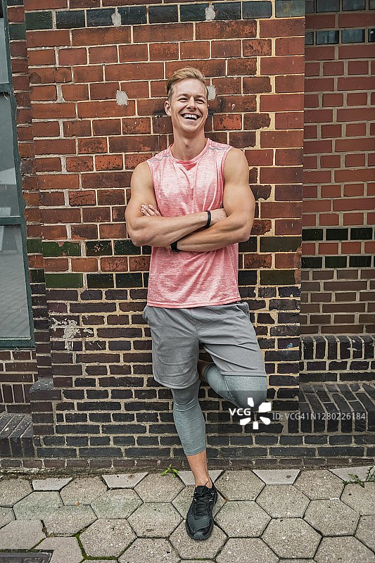 站在墙前的健壮男运动员图片素材