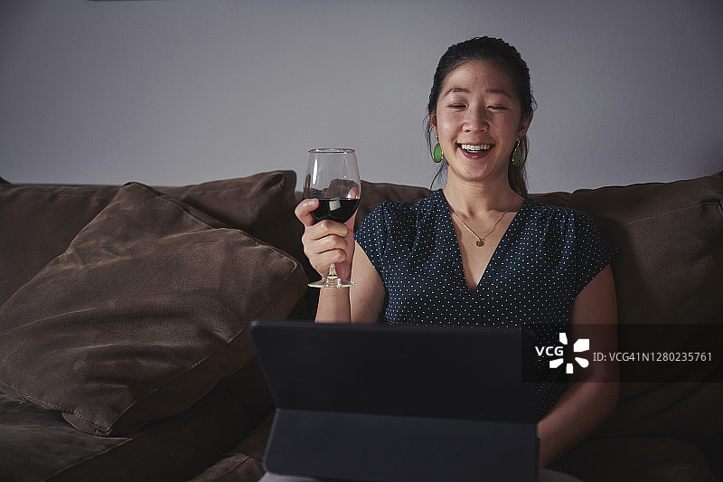 女人在视频聊天中与朋友碰红酒杯图片素材