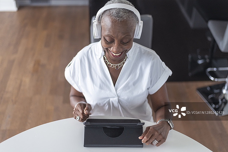年长黑人妇女在COVID-19期间使用平板电脑连接图片素材