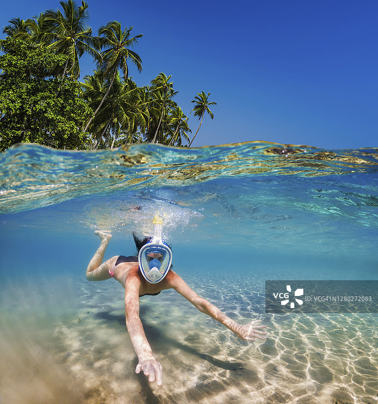 热带岛屿附近浮潜：水中畅游的女孩图片素材