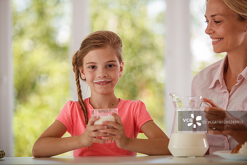 早上，快乐的小女孩在喝牛奶图片素材